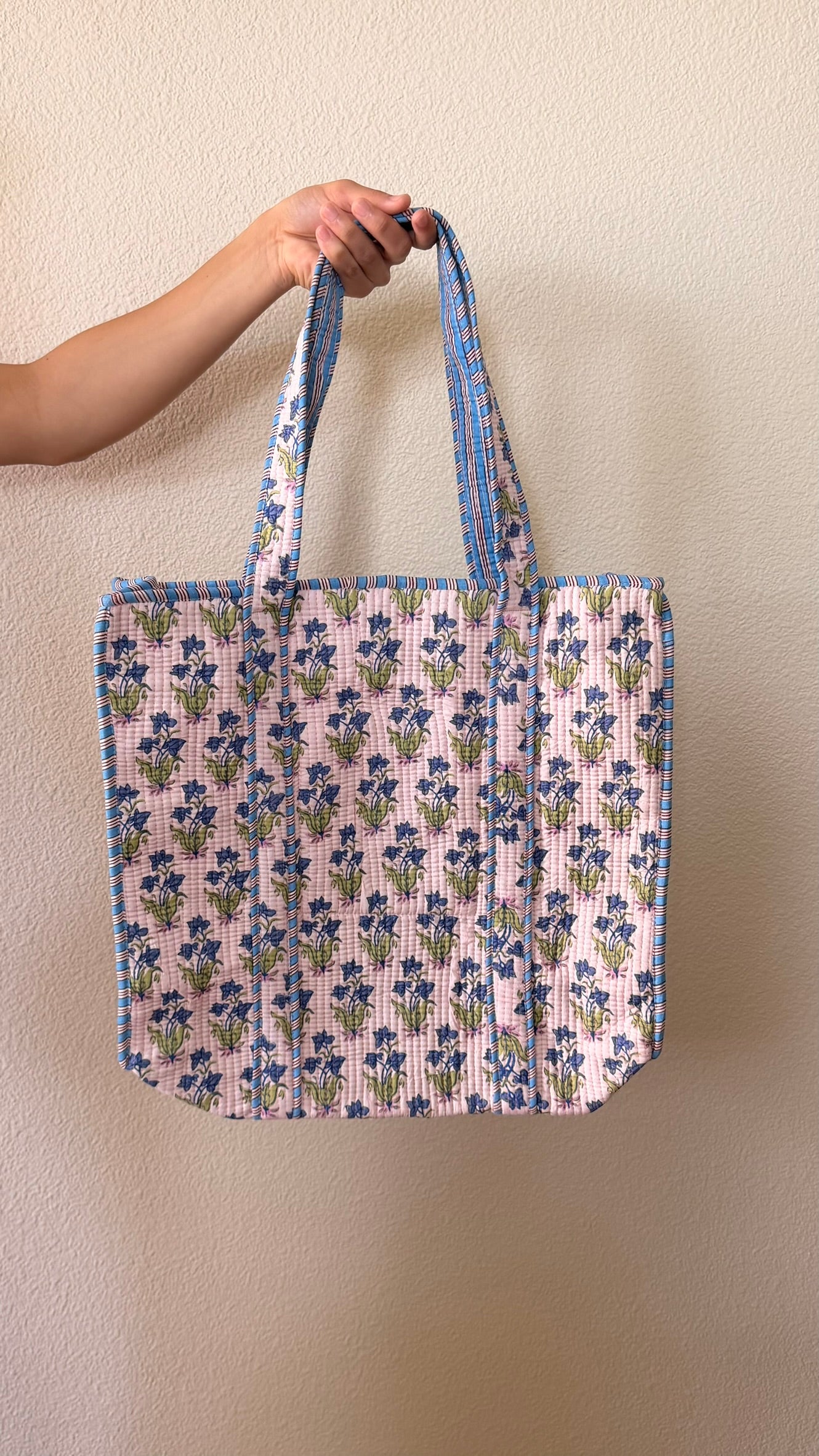 Hand-block printed quilted cotton tote bag. Featuring delicate blue blossoms and fresh green leaves on a soft blush-pink backdrop.