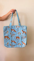 Hand-block printed quilted cotton tote bag. Featuring foxes, deer, owls, and raccoons wander across a soft sky-blue backdrop.