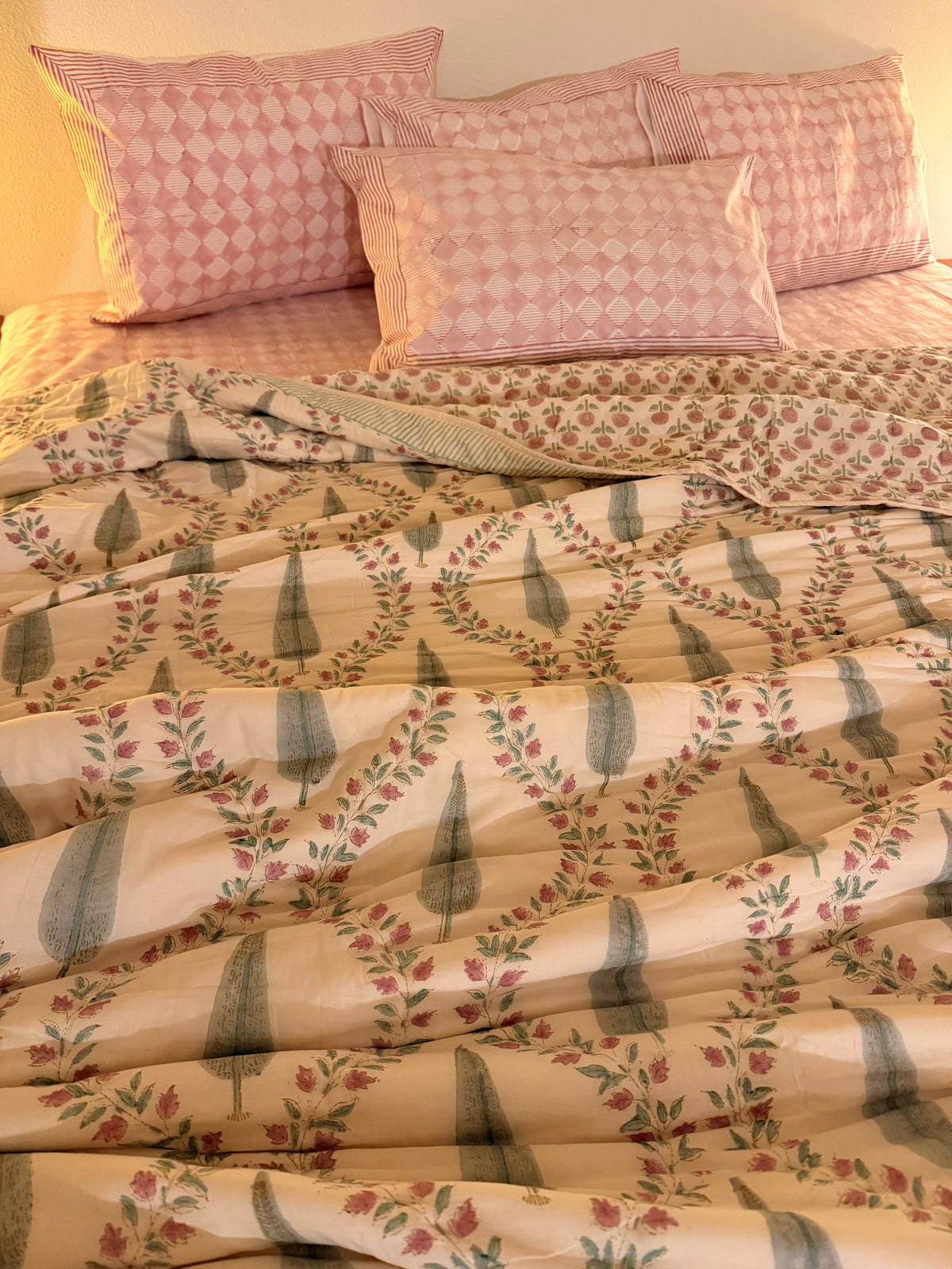 600 TC south cotton pink block print bedsheet set with pillows styled with a block print reversible quilt to create a cozy bed.