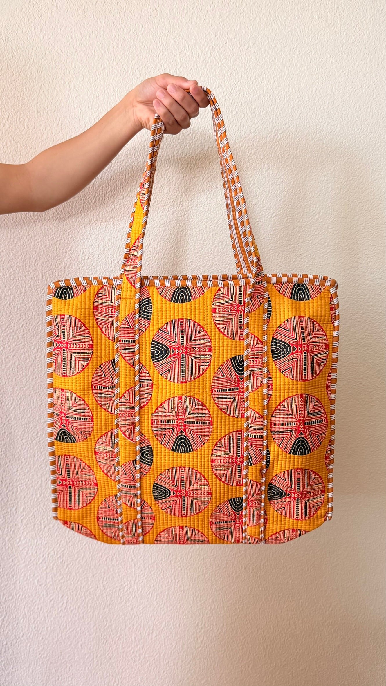 Hand-block printed quilted cotton tote bag. Bold bright orange with circular geometric patterns.