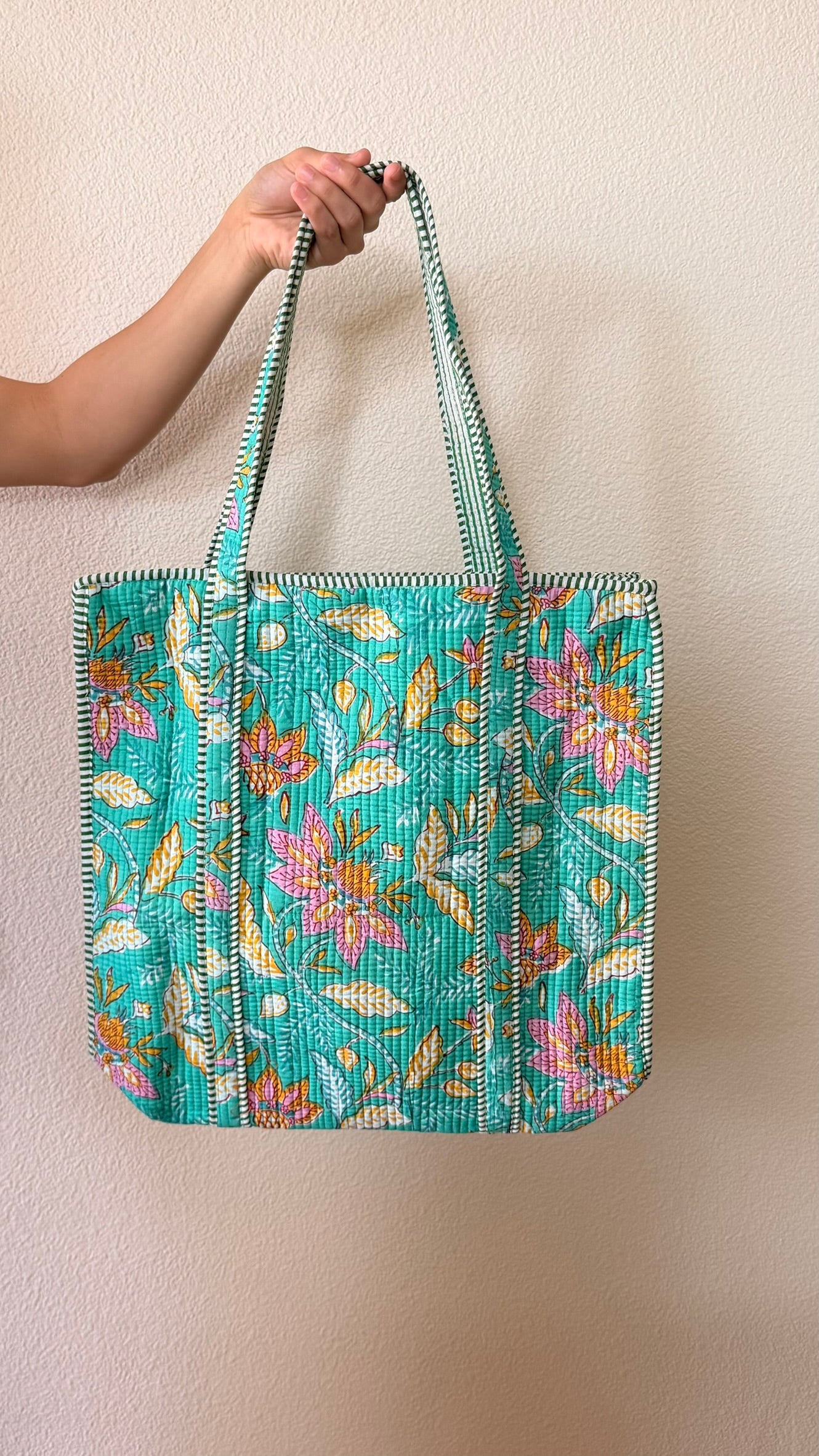 Hand-block printed quilted cotton tote bag. Featuring turquoise backdrop, playful pink florals, golden leaves, and winding botanical details.